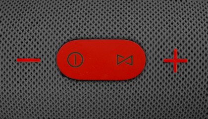 Wireless music speaker. Red control and volume buttons on gray bluetooth speaker. Wallpaper and...