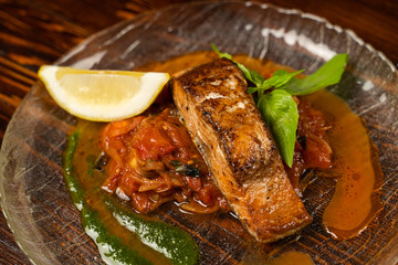Close up of chum salmon marinated in lemon juice with stewed vegetables on wooden table