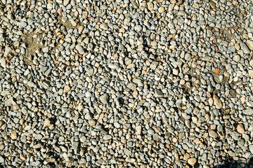 Abstract brown-gray background. Multi-colored and different-sized stone pebbles. Gravel scattered on the ground