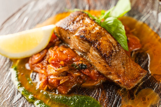 Close up of chum salmon marinated in lemon juice with stewed vegetables on wooden table