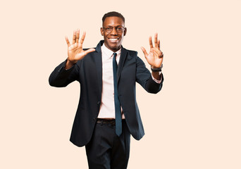 african american businessman smiling and looking friendly, showing number nine or ninth with hand...