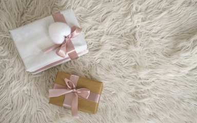 Top view of White and brown gift boxes with pink ribbon on white fluffy rug