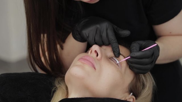 A professional beautician in a beauty salon applied a special gel for eyelash lamination to eyelashes.
