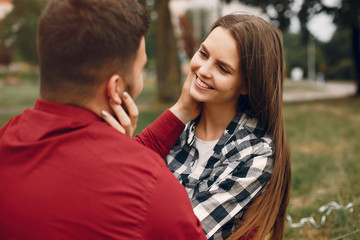 Obraz premium Cute couple in a park. Lady in a chirt. Guy in a red shirt