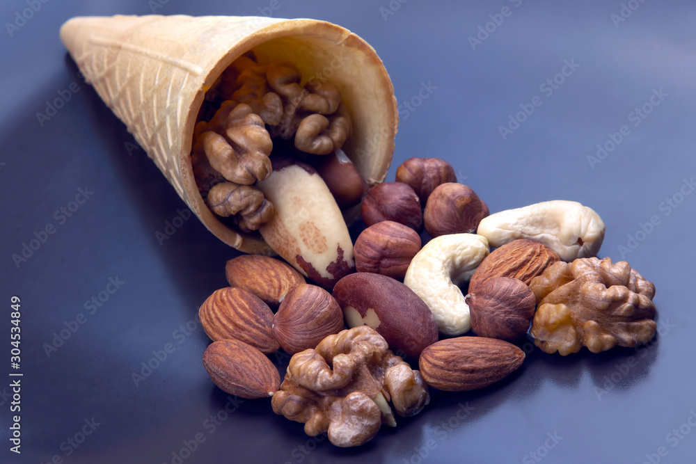 Wall mural different types of nuts in a waffle cone on a gray background. healthy and protein food