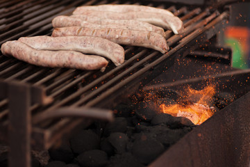 Sausages fresh on a grill that's throwing sparks