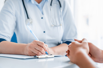 Close up of doctor and patient sitting at the desk in clinic