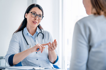 Smiling female doctor giving advice to female patient in cabinet