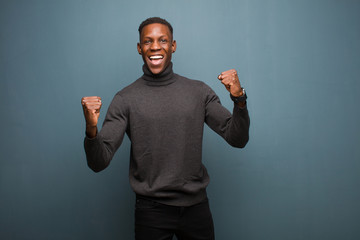 young african american black man shouting aggressively with an angry expression or with fists...