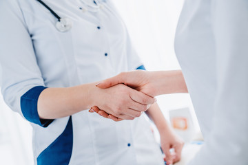 Close up of woman doctor shaking hands with patient