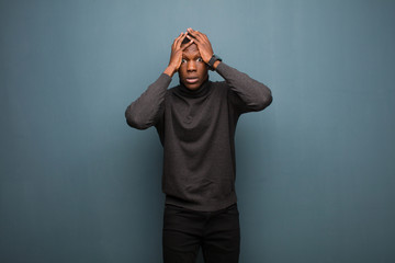 young african american black man feeling horrified and shocked, raising hands to head and panicking...