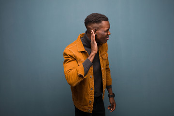 young african american black man looking serious and curious, listening, trying to hear a secret...