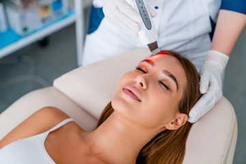 Naklejka premium Cosmetologist make face while procedure ultrasound facial peeling in cosmetology cabinet