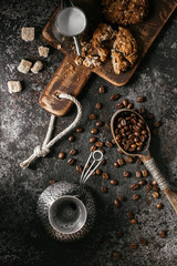 Coffee beans with coffee and cookie on dark textured background.