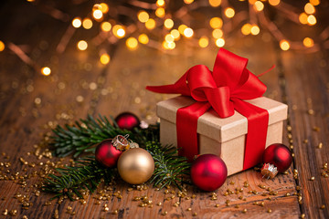 Christmas gift box , fir branches and baubles on rustic wooden table  -  Bokeh lights in background...