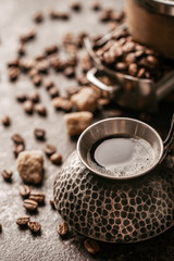 Coffee cup and coffee beans on dark stone background.