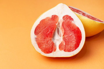 Fresh grapefruit on an orange background, close-up. Sex concept. The concept of women's health.