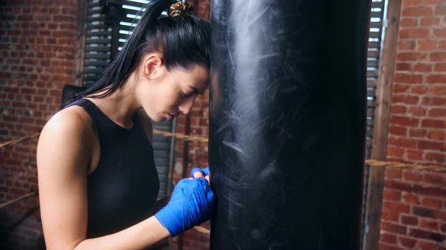 Ferocious mixed race sportswoman threatening beating sport equipment by arms in gloves