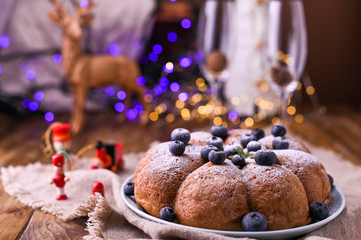 Christmas cake with berries and icing sugar on a wooden background. Traditional pastries in Italy. Bokeh on background