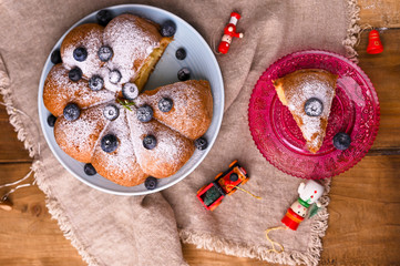 Christmas cake with berries and icing sugar on a wooden background. Traditional pastries in Italy. Above