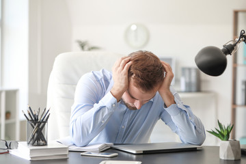 Young man suffering from headache in office