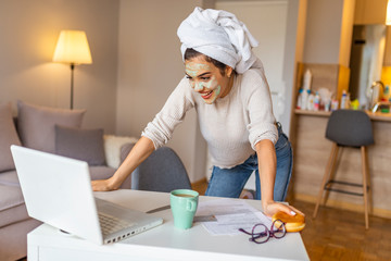 Attractive young woman with face mask surfing the net from her home. Business, people and technology concept - happy smiling woman with laptop computer working at home