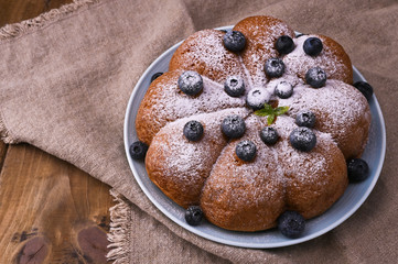 Christmas cake with berries and icing sugar on a wooden background. Traditional pastries in Italy.