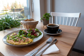Vegetarian meal for healthy breakfast in the morning in restauranr. Omelette with salad and black coffee. Tasty food.