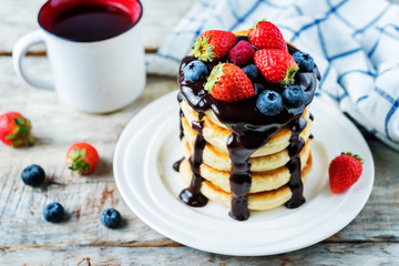 pancakes with chocolate glaze, strawberries, blueberries and raspberries