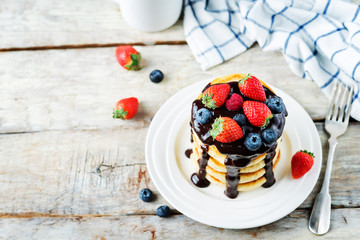 pancakes with chocolate glaze, strawberries, blueberries and raspberries
