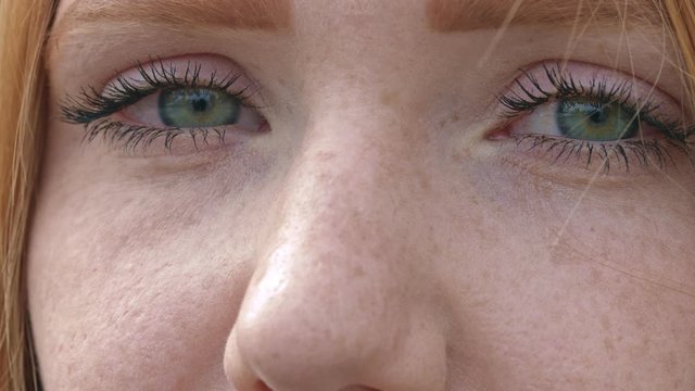 sad eyes of woman with freckles blink, still extreme close up shot 