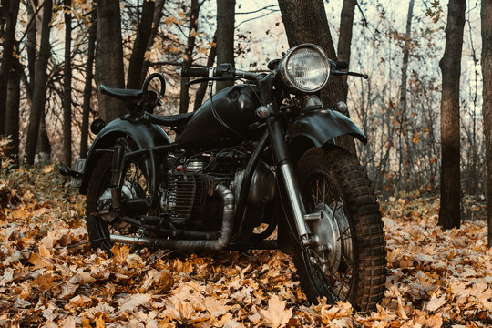 Black old russian motorbike K 750 in autumn wood. Close up