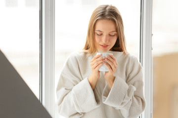Young woman with cup of hot tea resting at home