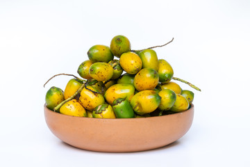 Pottery bowl with ripe and delicious pupunha palm fruit (Bactris gasipaes), harvested from the Amazon rainforest, isolated on white background. Concept of healthy eating, health, cooking and nature.
