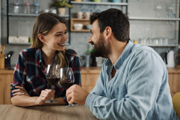 Young couple in love enjoying in conversation while drinking red wine