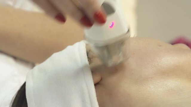 Young woman undergoing procedure of rf lifting in beauty salon, close up