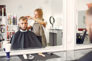 Man with a beard. Hairdresser with a client. Woman with scissors and a comb