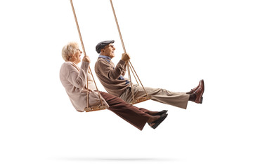 Elderly man and woman swinging on a wooden swings