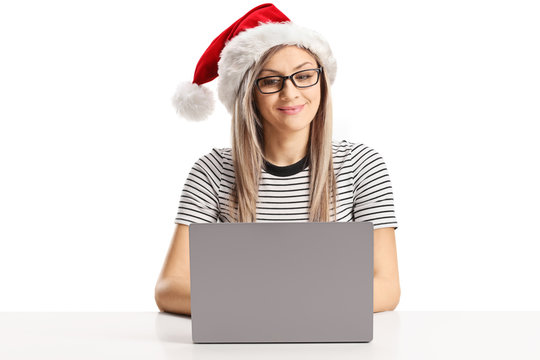Young woman working on a laptop and wearing a Santa Claus hat