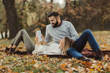 Young happy couple reading book together in autumn