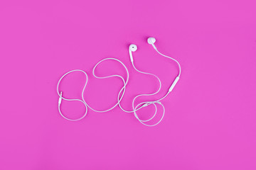 Obraz na płótnie Canvas White headphones for music on a pink background. View from above.