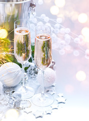 Christmas and New Year celebration with champagne. Holiday dinner table setting with Christmas tree decoration, two flutes of sparkling wine on served table, holiday Xmas dinner. Champagne