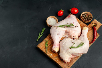 Raw chicken legs with spices and herbs, ready for cooking on a stone background, with copy space...