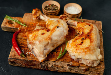Two fried chicken legs on a stone background with spices, ready to eat