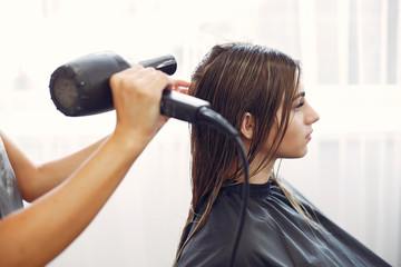 Fototapeta premium Hairdresser drying head her client. Woman in a hair salon