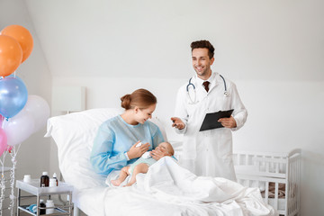 Obraz premium Young woman with newborn baby and gynecologist in maternity hospital