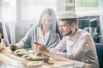 key opinion leader millennial woman or girl makes selfie on smartphone   camera to share on internet social media channels.couple in a cafe   smiling looking at the phone