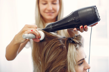 Fototapeta premium Hairdresser drying head her client. Woman in a hair salon