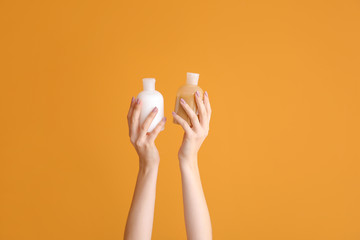 Female hands with different cosmetic products in bottles on color background