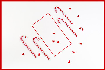 Modern Christmas background with red frame, candy canes and confetti in red and white 